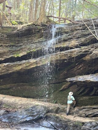 A Person Standing Next To A Waterfall From Robert Shepard