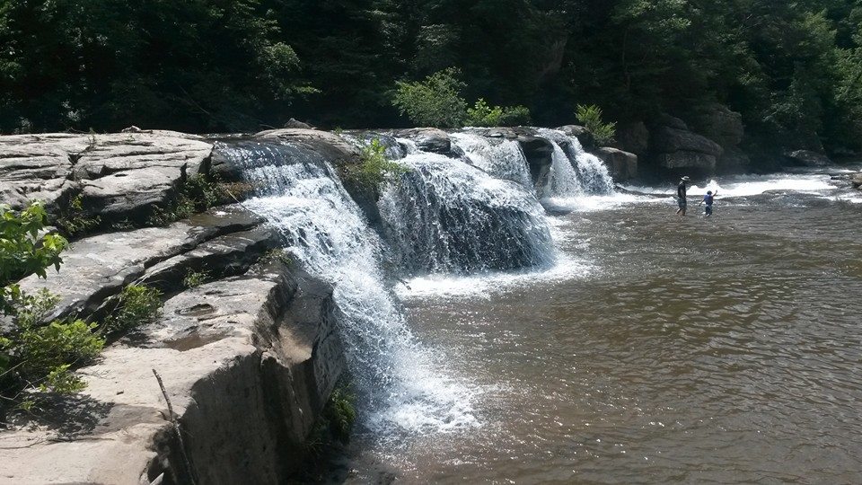 A father and son playing at at the bottom of a waterfall