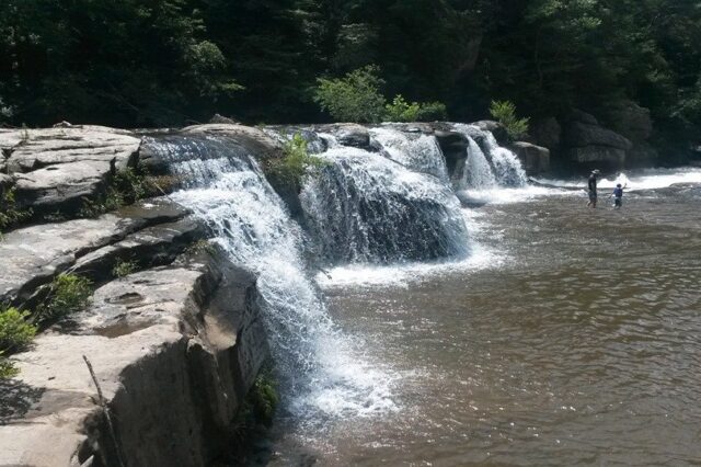 A Father And Son Playing At At The Bottom Of A Waterfall