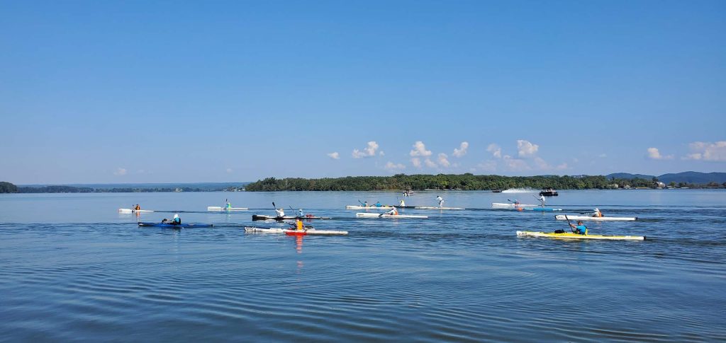 A Group Of People Rowing A Boat In A Body Of Water