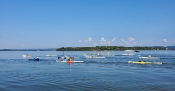 A Group Of People Rowing A Boat In A Body Of Water