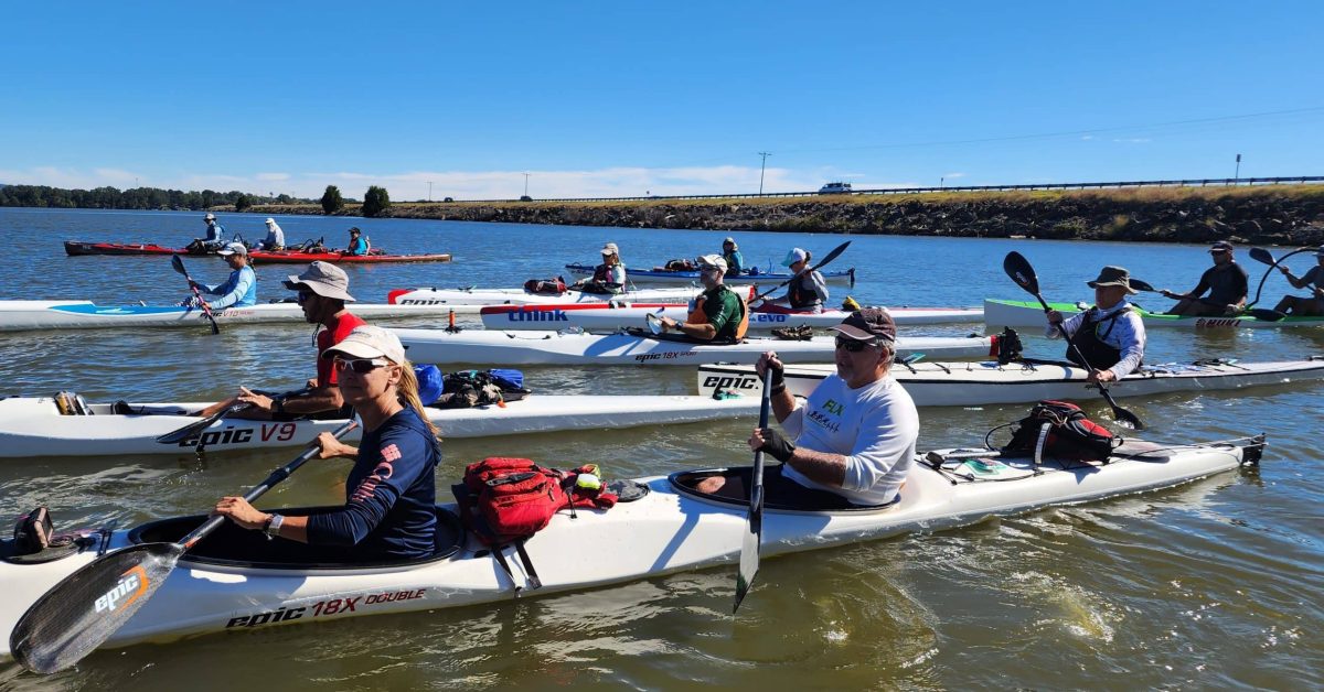 A Group Of People Rowing A Boat In The Water